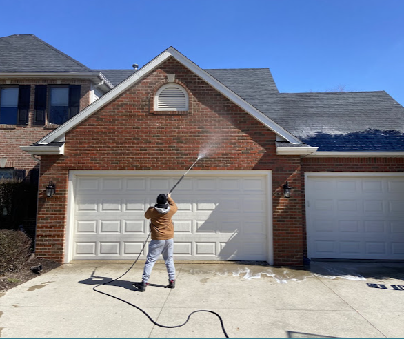 Pressure washing a brick garage and driveway